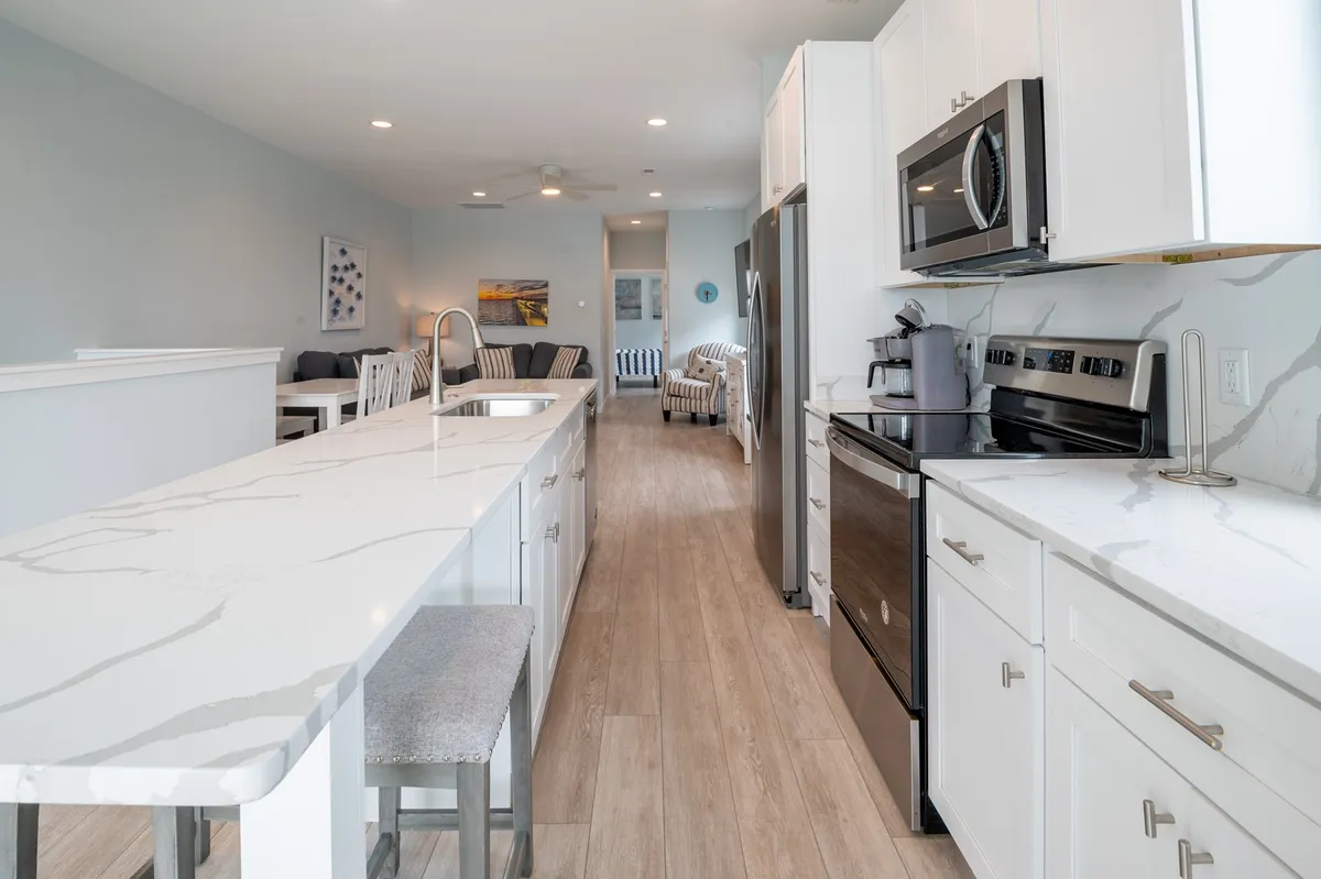The spacious kitchen features a prominent island with seating, gleaming stainless steel appliances, and an open, modern layout. Light cabinetry and welcoming décor suggest a space ideal for meal preparation and gathering.