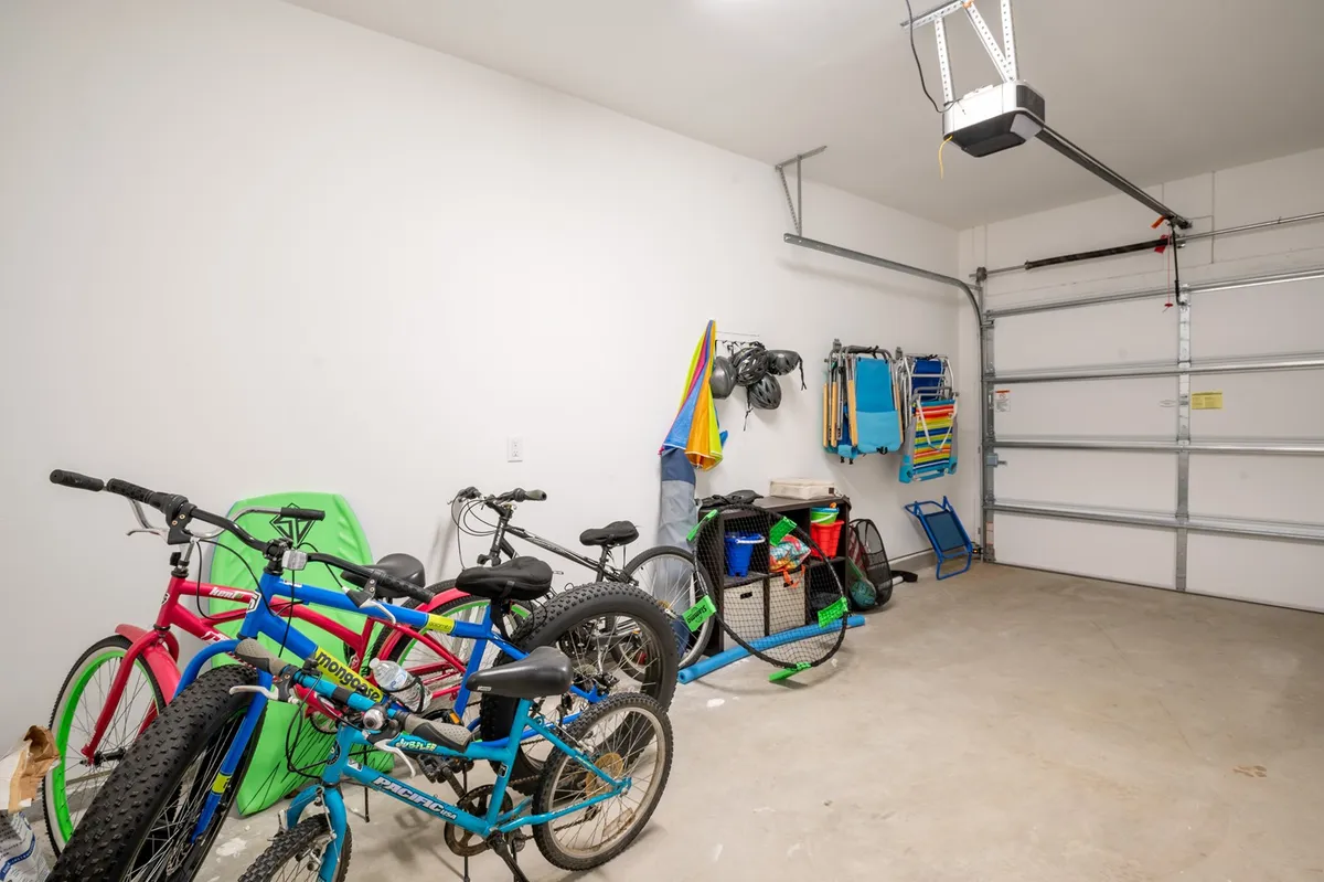 Inside the garage, this image focuses on a row of bicycles, colorful hanging towels, and organized storage bins—setting the scene for spontaneous adventures and easy access to outdoor gear. The playful arrangement hints at family bike rides and practical organization, extending the backyard lifestyle to nearby island exploration.