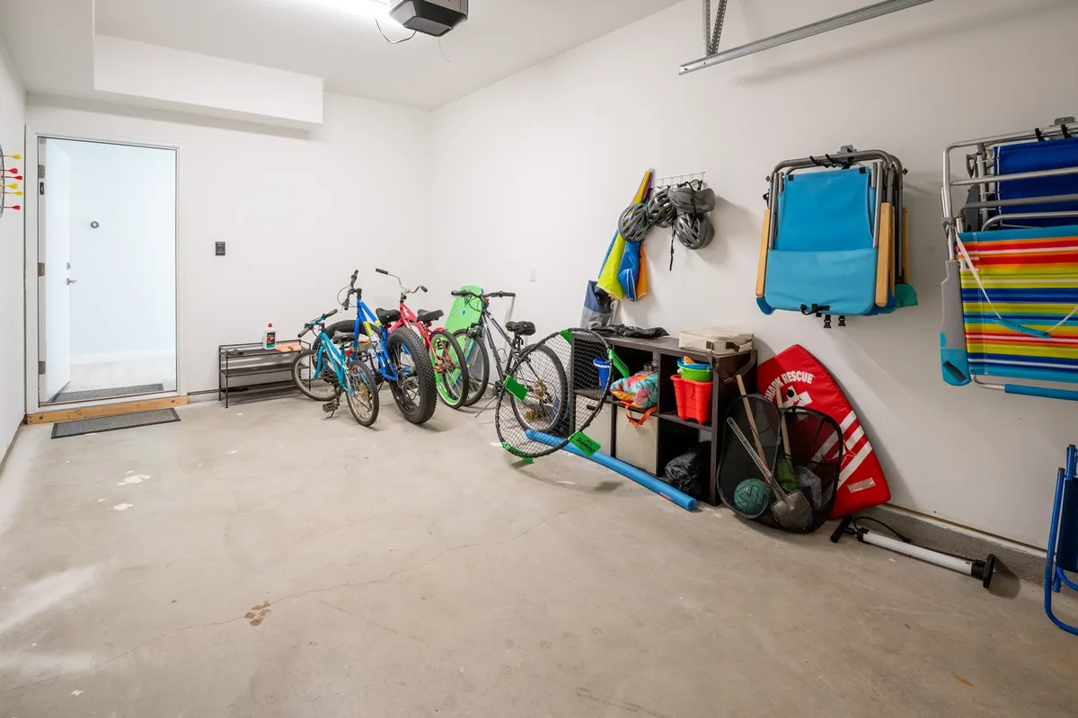 A practical storage area filled with bicycles and beach chairs, ready for a day of coastal adventure. The entry door nearby suggests easy access for families preparing for outings.